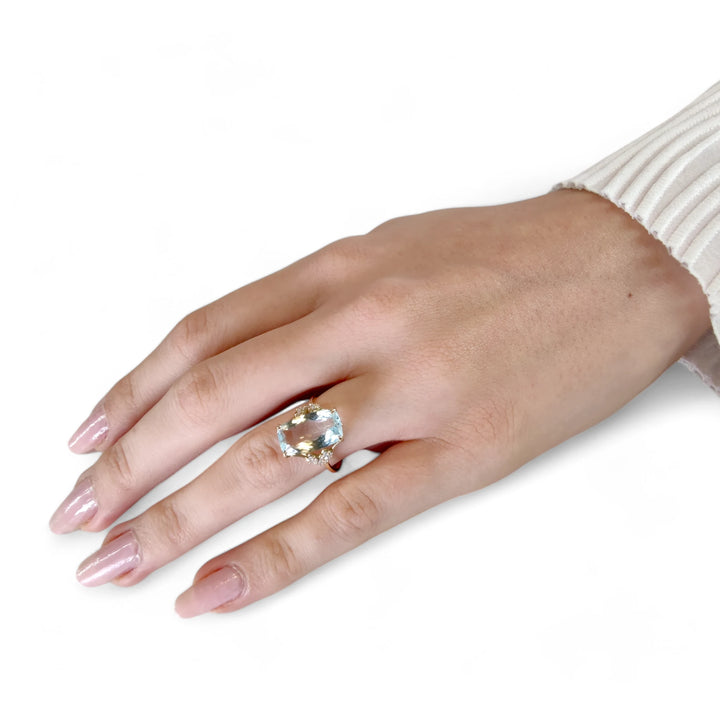 Elegant handcrafted ring with a rectangular cushion aquamarine and diamonds in 14K yellow gold, worn by a female model showcasing her full hand