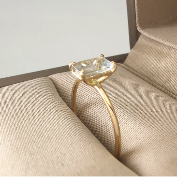 Side view of a solitaire aquamarine ring in 18K yellow gold displayed in a jewelry box