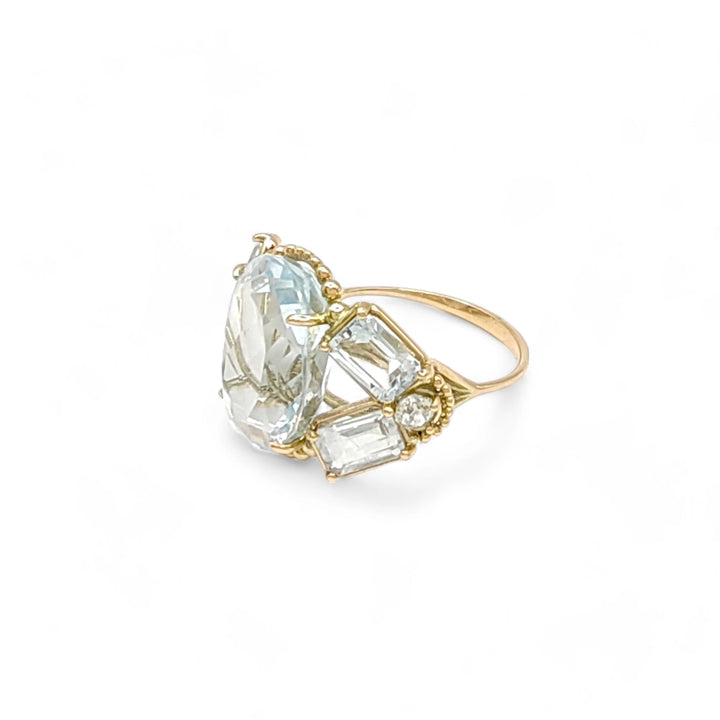 Horizontal left side view of a handcrafted vintage-style 14K yellow gold cocktail ring featuring aquamarines and diamond accents