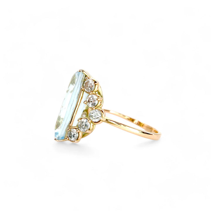 Left side view of a fine jewelry engagement ring in 14K yellow gold featuring a central aquamarine and five diamonds forming a V design