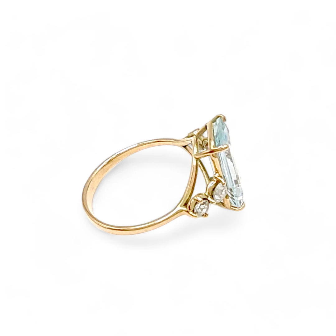 Right side horizontal view of a timeless 14K yellow gold engagement ring featuring a natural emerald-cut aquamarine and diamonds