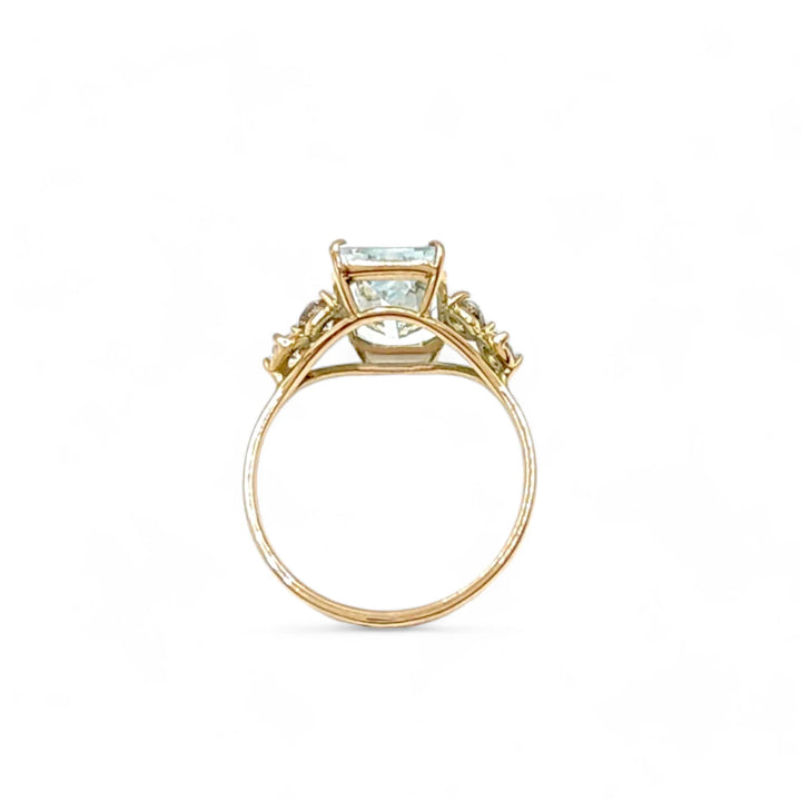 Vertical front view of a unique 14K yellow gold engagement ring with an emerald-cut aquamarine centerpiece and diamond detailing, black friday 