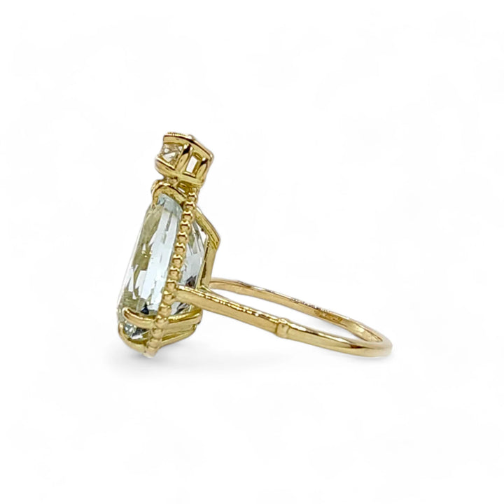 Left side view of a handcrafted 18K yellow gold ring with a pear-cut aquamarine and a diamond in a vintage design