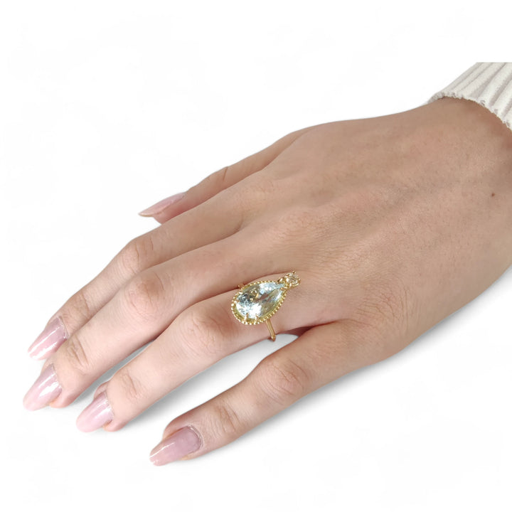 Beautiful aquamarine and diamond ring in 18K yellow gold worn on a model’s hand in a vintage engagement style