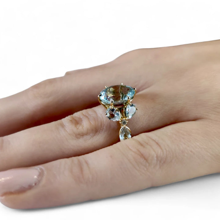 Close-up of a women’s oval aquamarine and diamond floral ring worn on a model’s hand, showcasing its fine craftsmanship and artistic design

