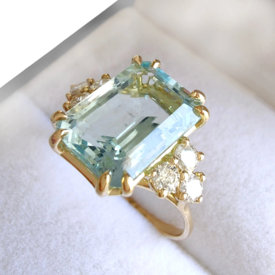 Side view of a jewelry box displaying an 18K yellow gold engagement ring with a large emerald-cut aquamarine and cathedral-style diamonds, ideal for buyers seeking a unique and luxurious engagement ring