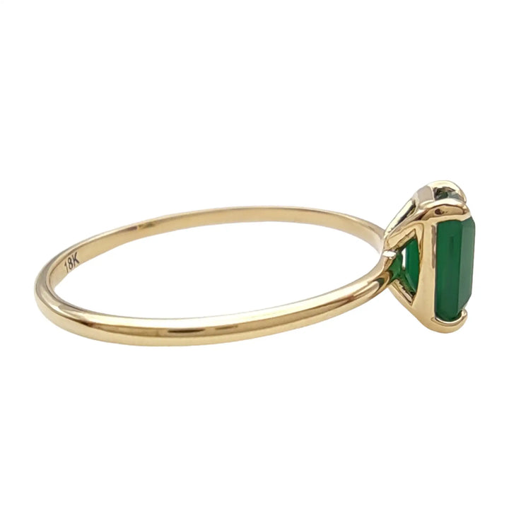 Right side view of an 18K yellow gold solitaire emerald engagement ring, showcasing the gemstone's brilliance and luxurious design