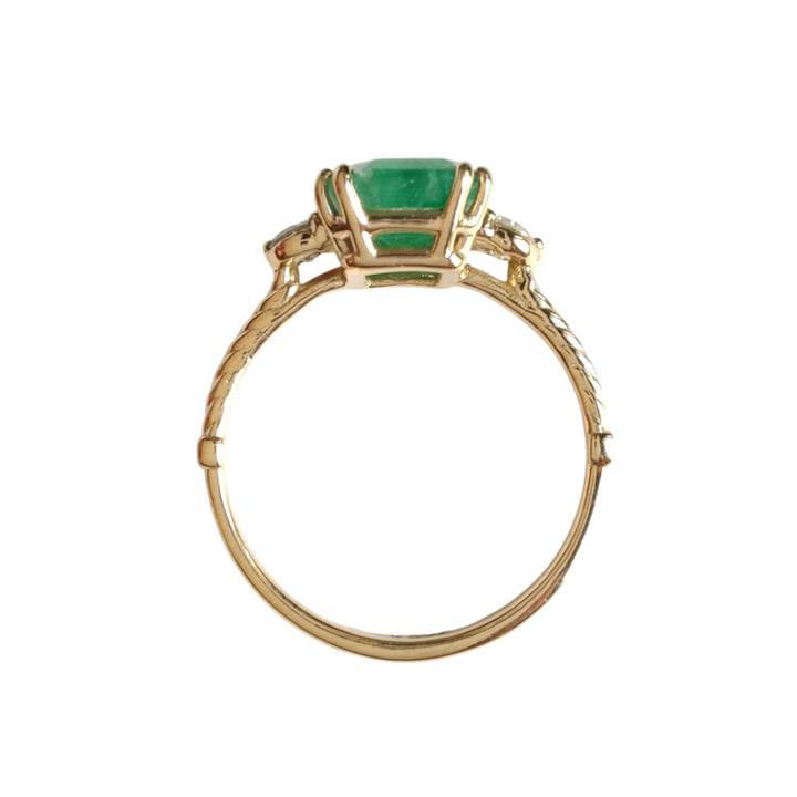 Front vertical view of a three-stone engagement ring in 18K yellow gold, featuring a central emerald and diamonds, available to buy for a special proposal or Christmas gift