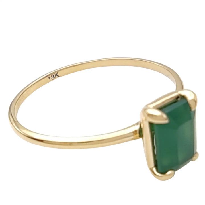 Oblique view of a solitaire emerald engagement ring in 18K yellow gold, displaying the refined details and elegant craftsmanship.