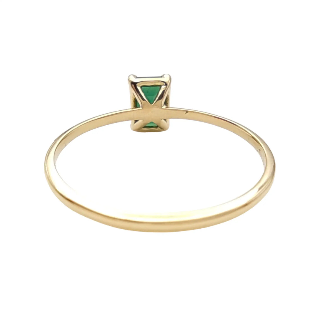 Back view of a solitaire emerald engagement ring in 18K yellow gold, highlighting the secure setting and polished craftsmanship.