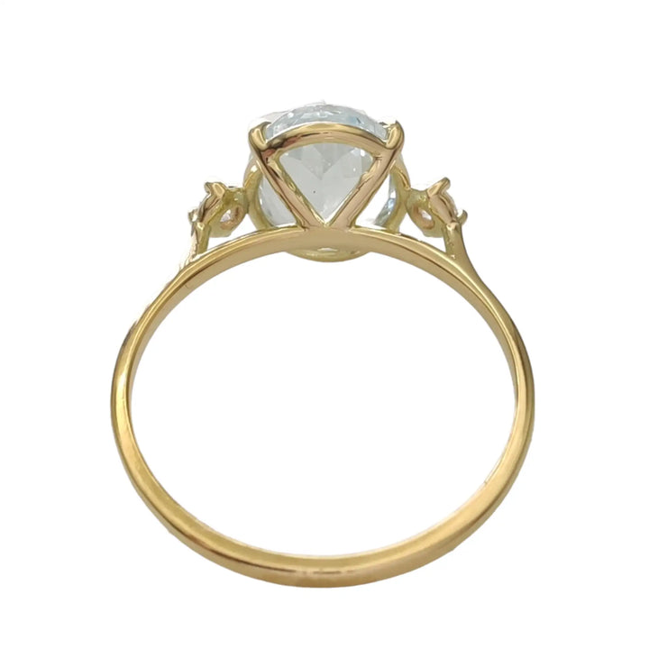 Back view of a buyable 18K yellow gold three-stone engagement ring featuring an oval aquamarine and diamond accents, ideal for engagements or as a memorable gift