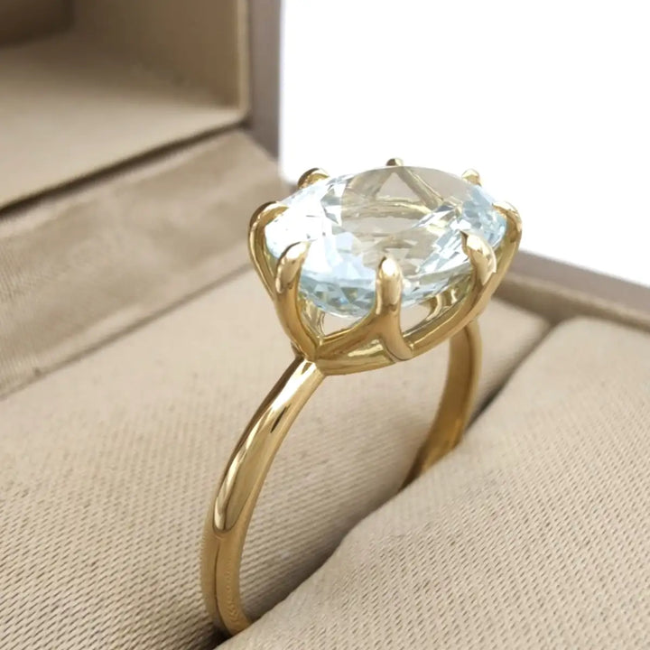 Solitaire aquamarine engagement ring in 18K yellow gold presented inside a jewelry box, making it a perfect gift to buy for engagement or Christmas