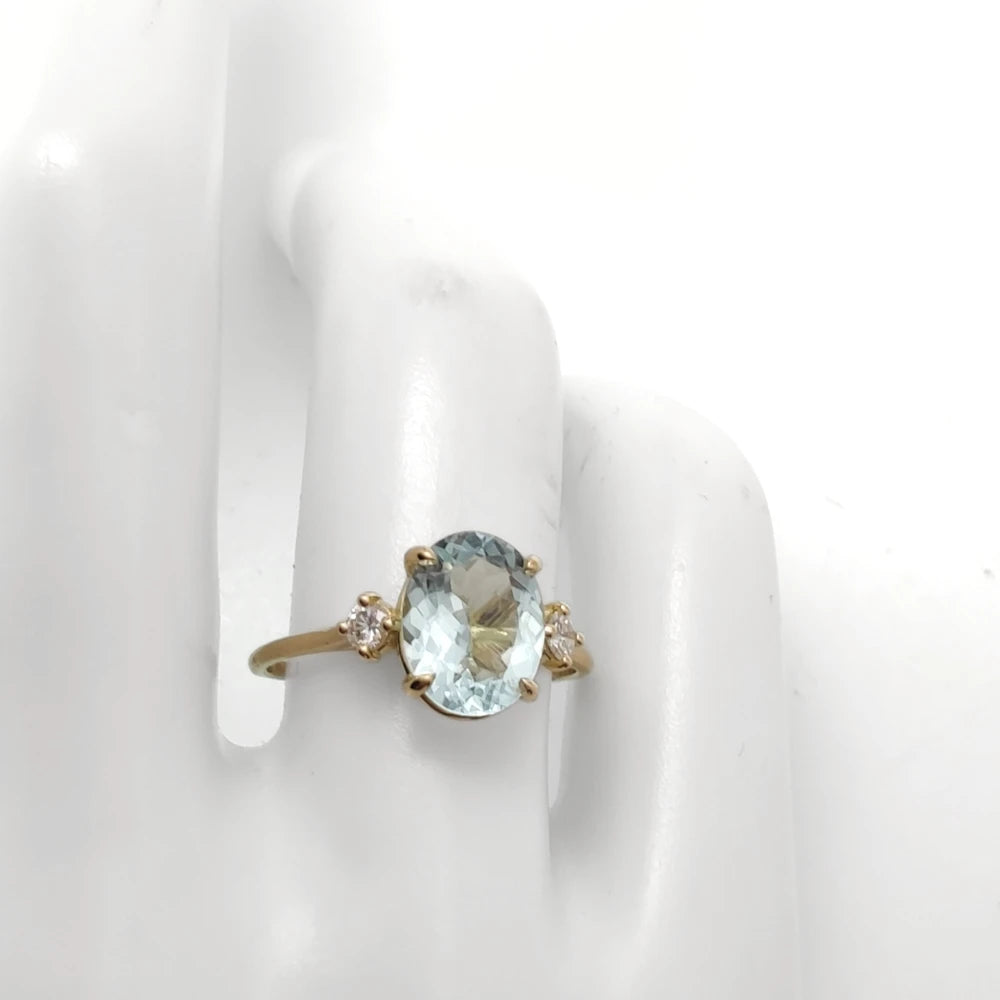 Various poses of a mannequin hand displaying an 18K yellow gold engagement ring with an oval aquamarine and diamonds, showcasing different angles and features of the ring