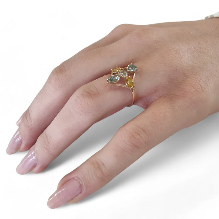 Full hand view of a model wearing a 14K yellow gold engagement ring with a central brilliant-cut diamond and blue and yellow marquise diamonds, perfect for buyers looking for a special gift