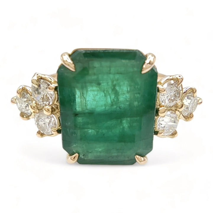 Front view of a 14K yellow gold engagement ring featuring a central emerald flanked by three diamonds on each side, perfect for proposing or as a sophisticated gift for a special occasion