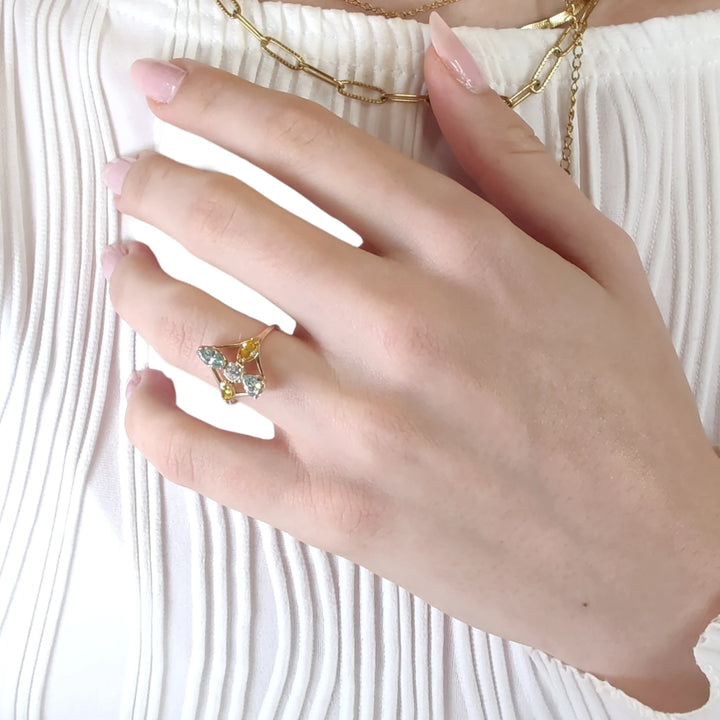 Second pose of a model's hand displaying a 14K yellow gold engagement ring with a mix of incolor and fancy colored diamonds, emphasizing its elegance and unique appeal