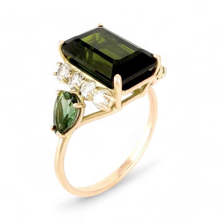 Vertical cover image of a 14K yellow gold engagement or cocktail ring featuring a dark green emerald-cut tourmaline, flanked by four brilliant diamonds and a pear-shaped green tourmaline on each side, perfect for a minimalist and contemporary Christmas gift