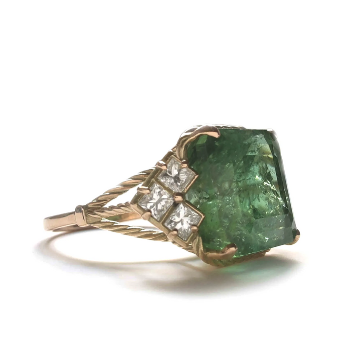 Right side view of a 14K yellow gold vintage engagement ring with a central green tourmaline and side diamonds, showcasing the sophisticated and curled arm design