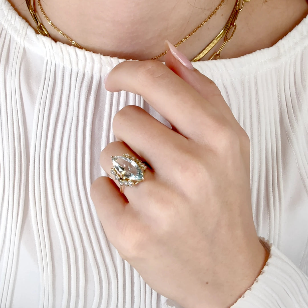 First pose of a model's hand wearing a 14K yellow gold marquise-cut engagement ring with diamonds, highlighting its sleek and contemporary design, perfect for gifting to a mother, friend, or partner