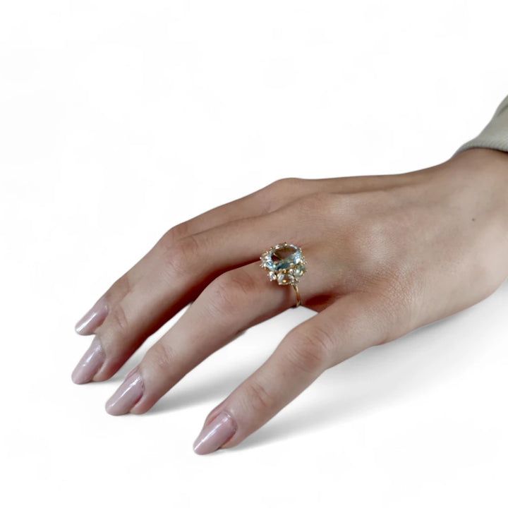 Full hand view of a model wearing a stunning 18K yellow gold engagement ring with aquamarines and diamonds, perfect for buyers looking for a statement piece