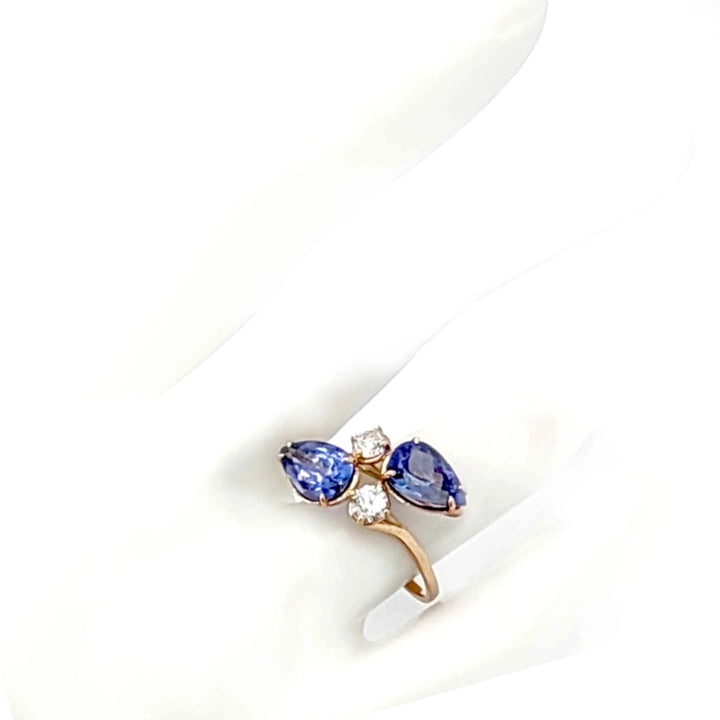 14K yellow gold engagement ring on a mannequin hand showcasing a bypass design with pear-cut tanzanite and brilliant diamonds, ideal for those seeking a unique engagement ring