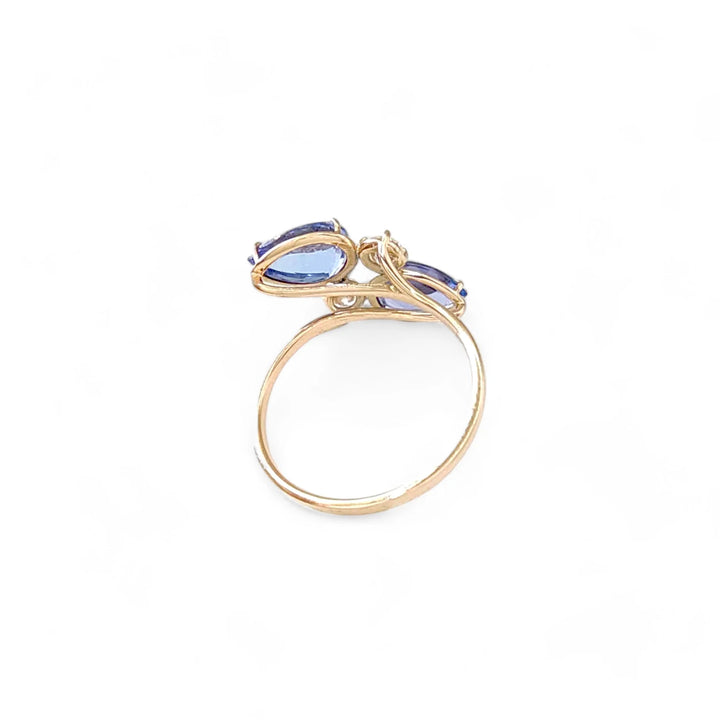 Back view of a 14K yellow gold bypass engagement ring featuring pear-cut tanzanite and brilliant diamonds, emphasizing the intricate craftsmanship and unique design