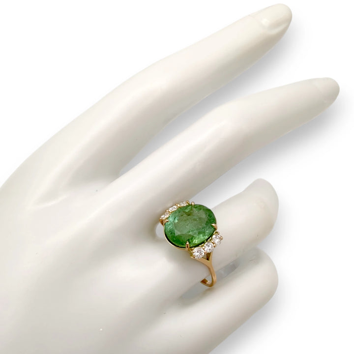 14K yellow gold engagement ring on a mannequin hand showcasing a central oval green tourmaline and six brilliant diamonds, ideal for those looking to buy a unique engagement ring