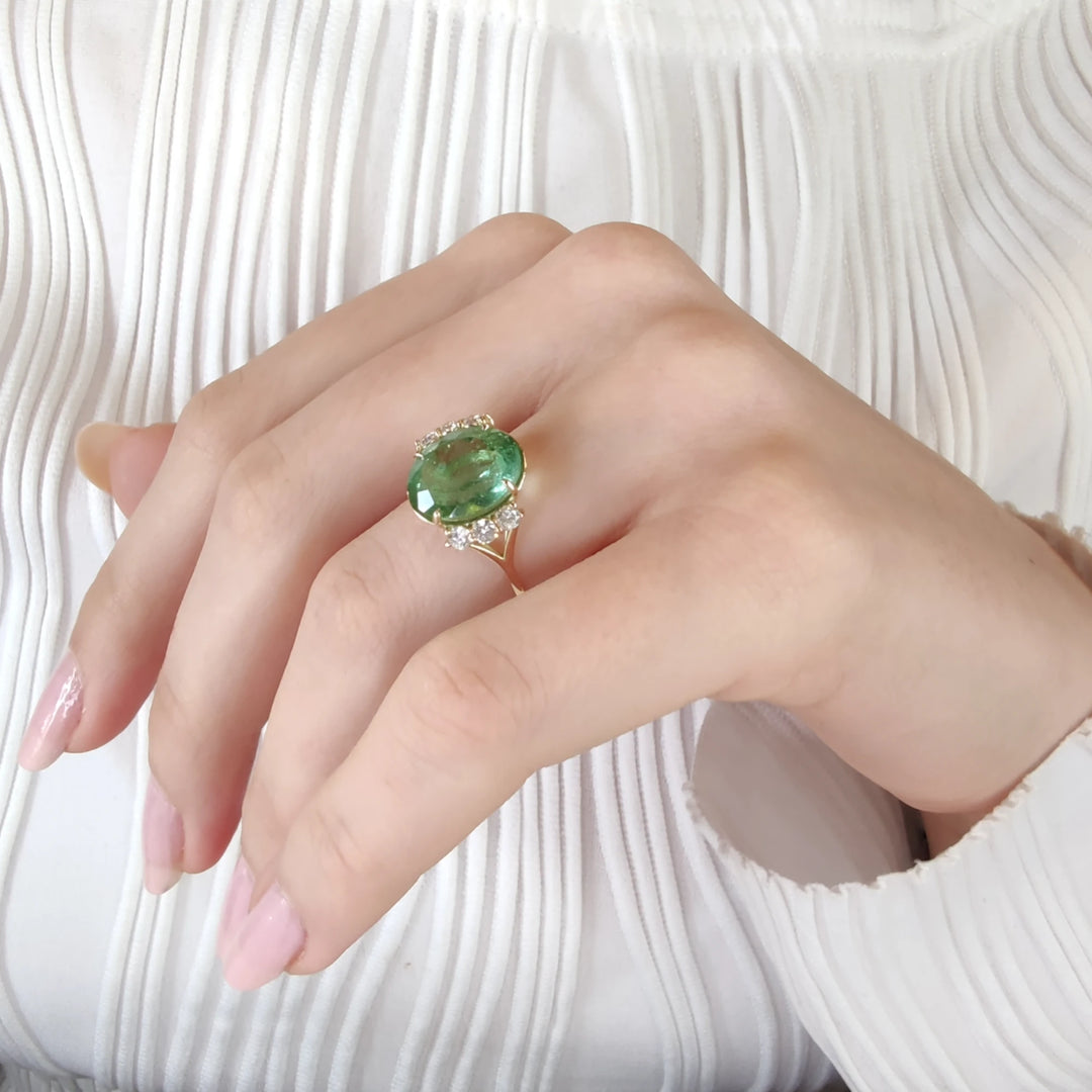 Second pose of a model wearing a 14K yellow gold ring with an oval green tourmaline and diamonds, highlighting the contemporary design and luxurious appeal