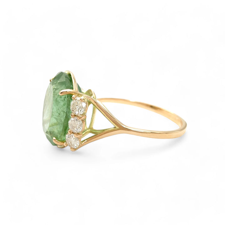 Left side view of a 14K yellow gold engagement ring with a central oval green tourmaline and diamond accents, showcasing the elegant and contemporary design