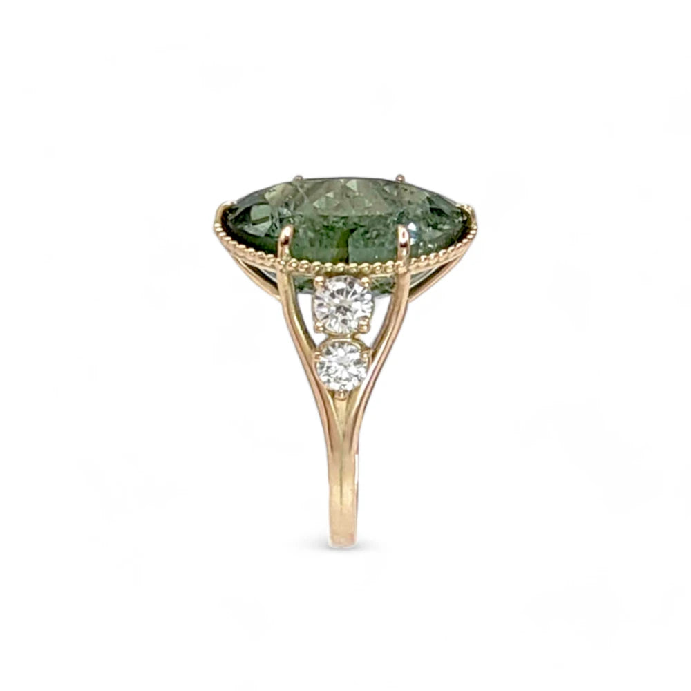 Vertical side view of a 14K yellow gold cocktail ring with an oval green tourmaline and diamonds, emphasizing the elegant miligrain detailing and contemporary style