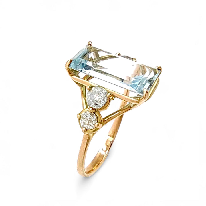 Vertical angled view of a women’s 14K solid yellow gold engagement ring featuring a natural emerald-cut aquamarine and two round diamonds on each side, perfect for Christmas or proposals