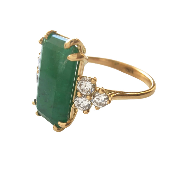 Left side view of a handcrafted 18K yellow gold engagement ring with an emerald centerpiece and diamond accents