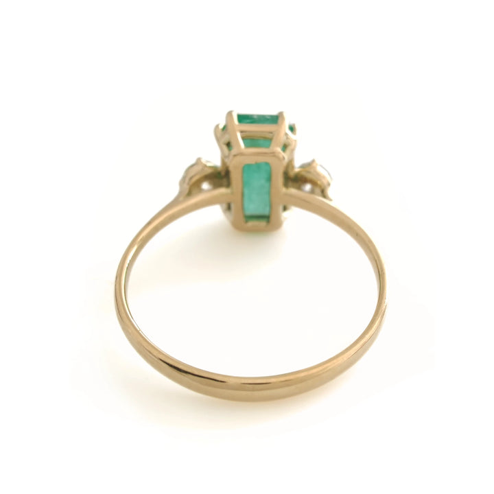 Back view of a handcrafted 18K yellow gold engagement ring featuring a central emerald and diamond accents, perfect for gifting