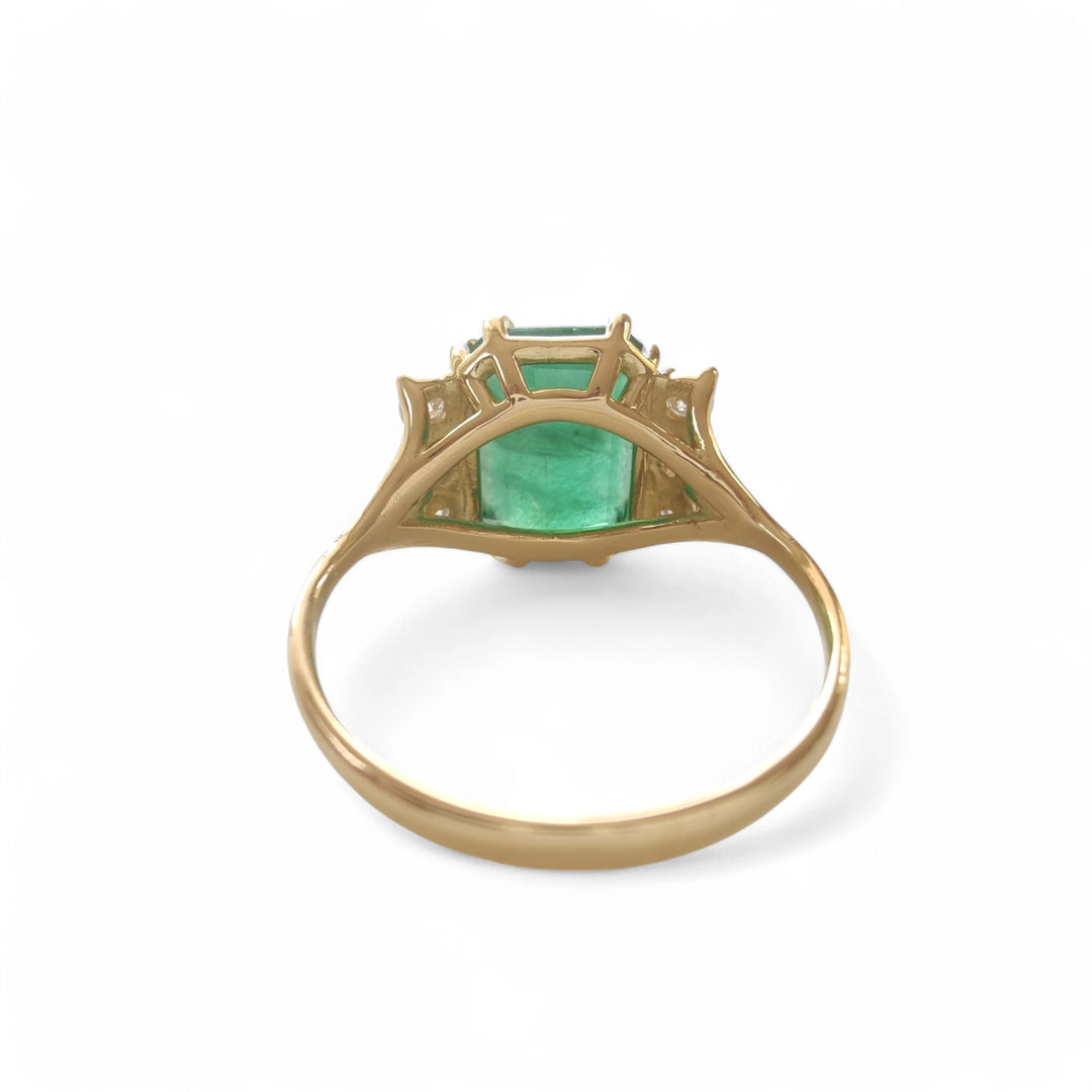 Back view of a unique engagement ring in 18K yellow gold with a central emerald and diamond detailing