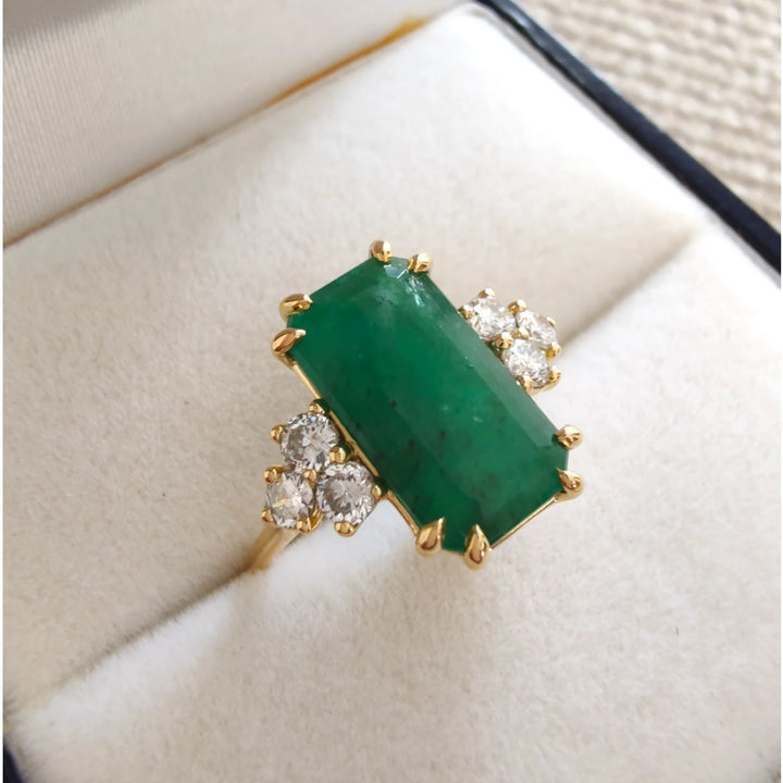 Elegant 18K yellow gold engagement ring with a central emerald and diamond accents, beautifully displayed in a jewelry box gift