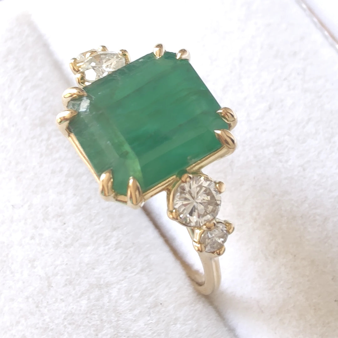 Elegant emerald and diamond engagement ring in 18K yellow gold displayed inside a jewelry box