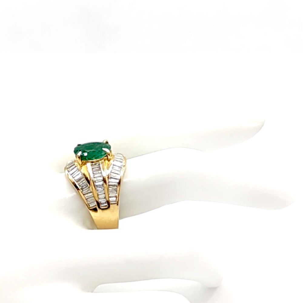 Side view of a stunning 22K gold cocktail ring displayed on a mannequin hand, showcasing an oval emerald center and elegant diamond baguette bands