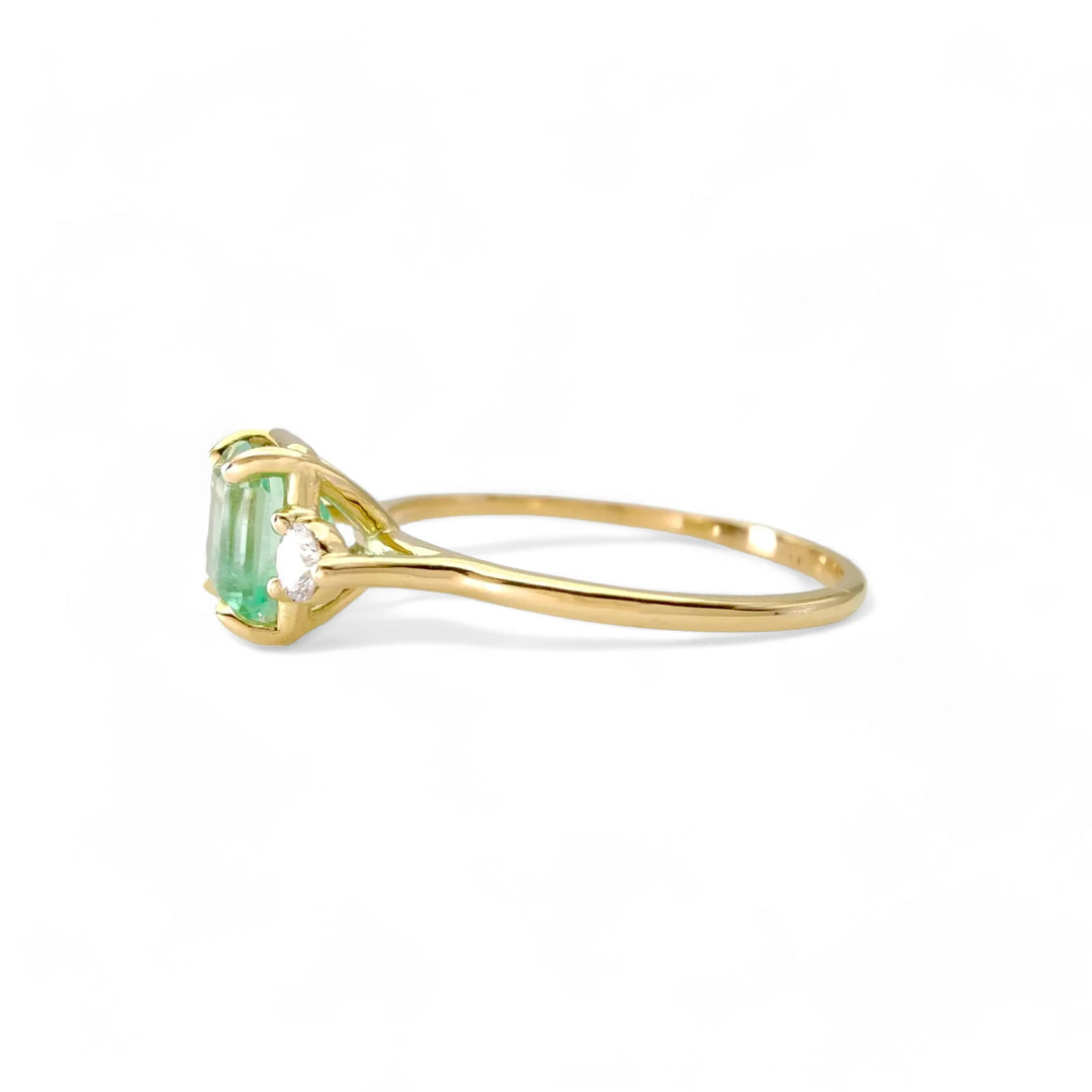 Lateral view of the 18K gold emerald engagement ring featuring diamonds. A handmade three-stone ring perfect for engagements and special occasions