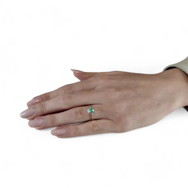 Full-hand view of the 18K gold emerald engagement ring with diamonds. Elegant three-stone design for engagements, weddings, or a memorable gift