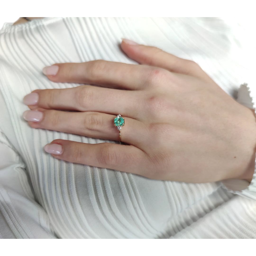 Third pose of a model showcasing the 18K gold emerald engagement ring. A timeless three-stone design ideal for engagements, weddings, and special gifts