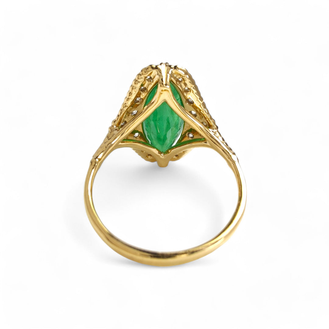 Back view of a fine 18K yellow gold engagement ring with a marquise emerald, diamond halo, and intricate milgrain design

