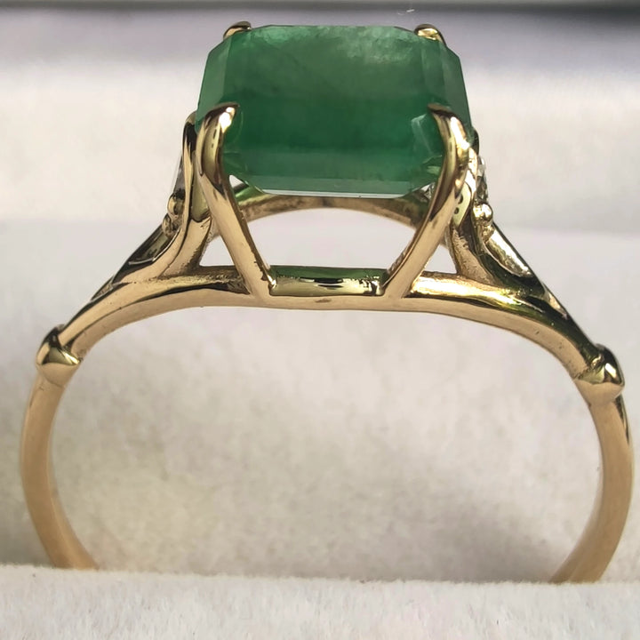 Front view of a handcrafted 18K yellow gold engagement ring featuring a central octagon emerald and a diamond on each side, ideal for anniversaries or special gifts