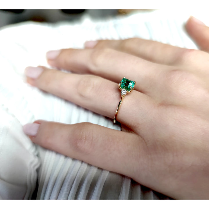 Beautiful 18K yellow gold ring with a central emerald and diamonds worn by a model for a classic engagement style