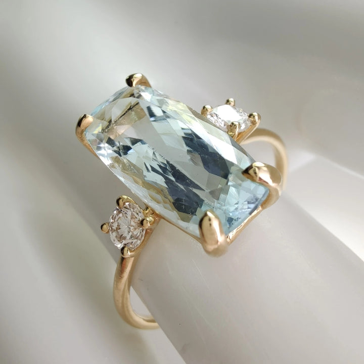  Engagement ring in 18K gold with aquamarine and diamonds, side view displayed on a white mannequin hand