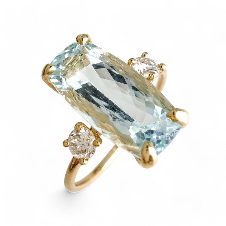 Alternative text: Engagement ring in 18K gold with aquamarine and diamonds, vertical view at a 45-degree angle on a white mannequin hand