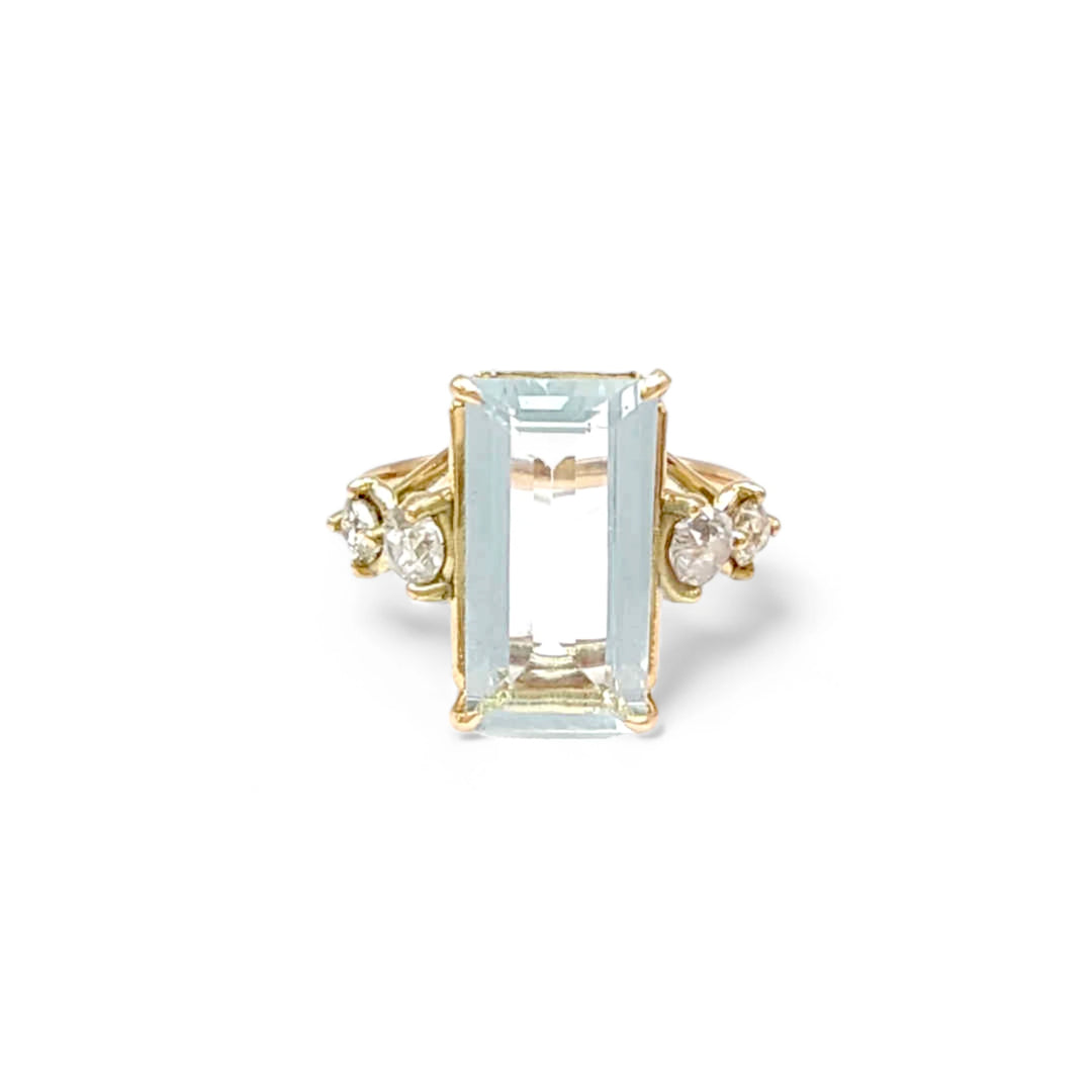 Front view of a handcrafted engagement ring in 14K yellow gold with a central emerald-cut aquamarine and two round diamonds on each side