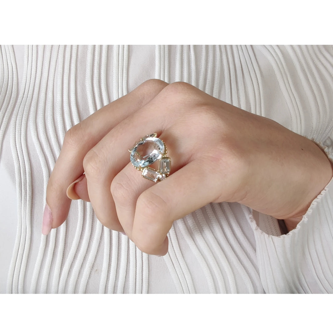 Beautiful vintage-inspired cocktail ring with aquamarines and diamonds in 14K yellow gold, worn on a model’s hand in pose 1