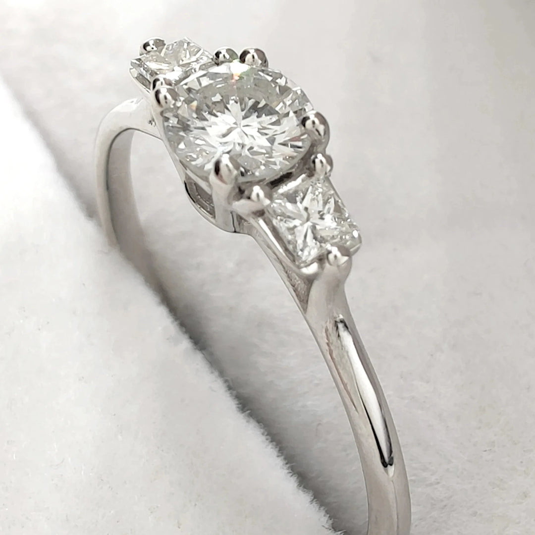 A stunning luxury white gold engagement ring featuring a brilliant round-cut diamond as the centerpiece. The elegant design is accentuated by two smaller diamonds on either side, creating a timeless and classic look perfect for proposals or special occasions