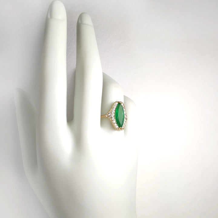 Full hand view of an elegant 18K yellow gold engagement ring with a marquise emerald, diamond halo, and milgrain band displayed on a mannequin