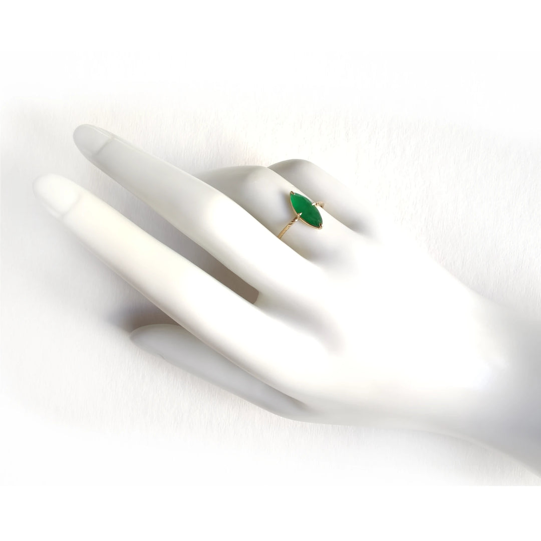 Elegant 18K yellow gold solitaire ring with a central marquise emerald and vintage-style band displayed on a mannequin hand